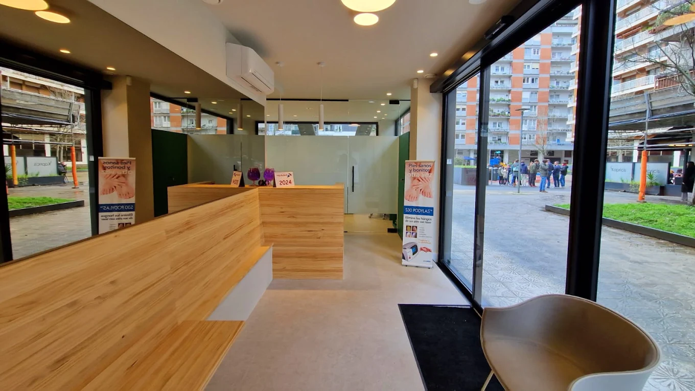 Recepción de la clínica con mostrador de madera, zona de espera y luz natural